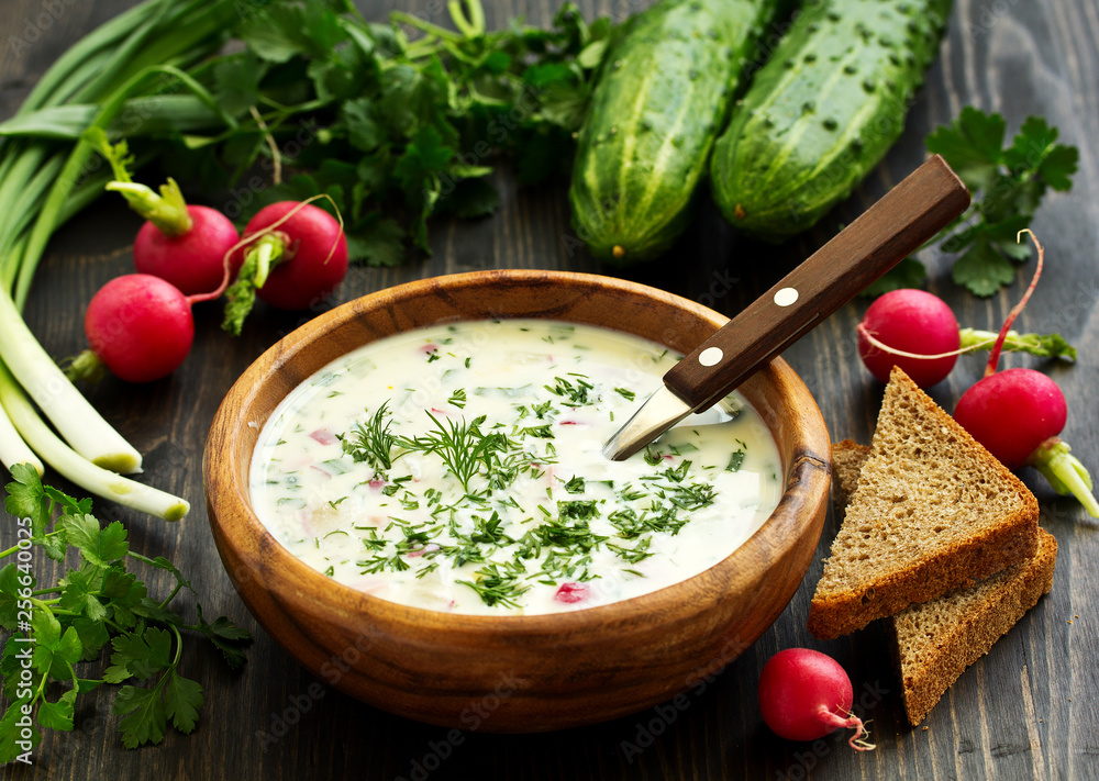 Fototapeta Okroshka. Summer light cold yogurt soup with cucumber, radish, eggs and dill on a wooden table. A traditional dish of Russian cuisine.