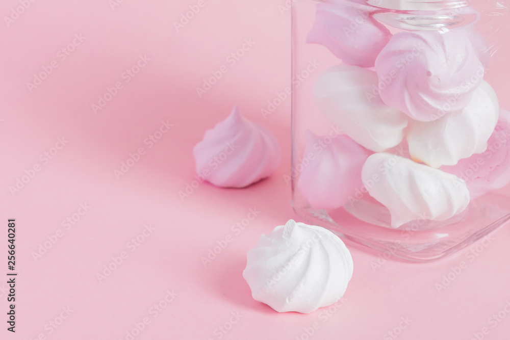White and pink twisted meringues in a glass jar on pink background. French dessert prepared from whipped with sugar and baked egg whites. Greeting card with copy space White and pink twisted meringues in a glass jar on pink background. French dessert prepared from whipped with sugar and baked egg whites. Greeting card with copy space