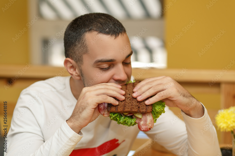 Hungry young man in resaurant eat sandwich Hungry young man in resaurant eat sandwich