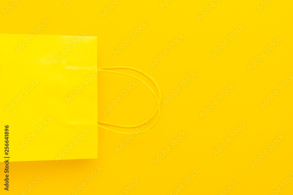 shopping paper bag on the yellow background with copy space. flat lay photo of upturned yellow bag. summer sale concept shopping paper bag on the yellow background with copy space. flat lay photo of upturned yellow bag. summer sale concept