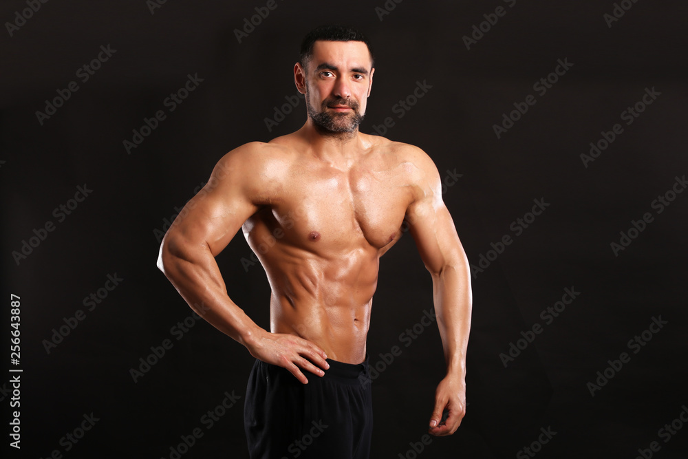 Portrait of young handsome  muscular bodybuilder on black background 