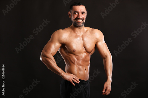 Portrait of young handsome  muscular bodybuilder on black background  © Bas