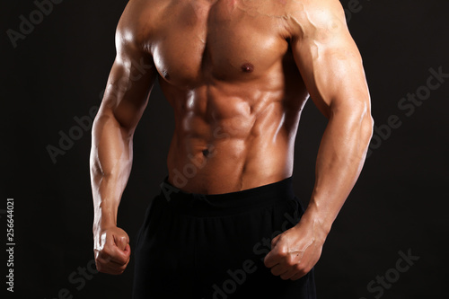 Portrait of young handsome muscular bodybuilder on black background torso close up view 