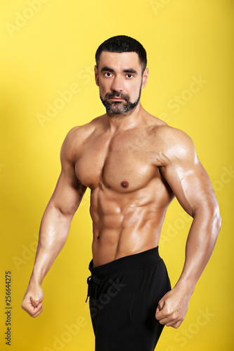 Portrait of young handsome  muscular bodybuilder on yellow background 