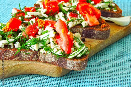 Toasts with white cheese and herbs with garlic on a small wooden board. Open sandwiches with selenium and cottage cheese. Garlic toast with grated mozzarella cheese and greens. 