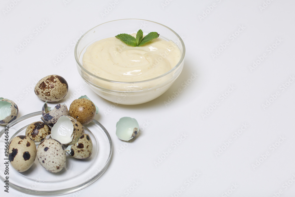 Handmade mayonnaise using quail eggs. In a glass container, decorated with greenery. Near quail eggs and shell from them. On a white background. Handmade mayonnaise using quail eggs. In a glass container, decorated with greenery. Near quail eggs and shell from them. On a white background.