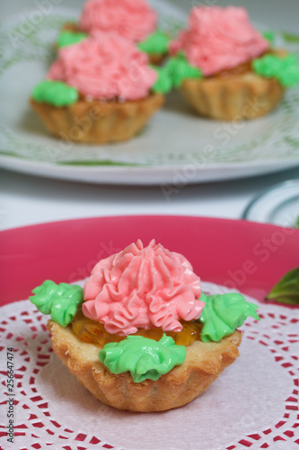 Basket cakes decorated with cream of different colors. Stuffing from jam.