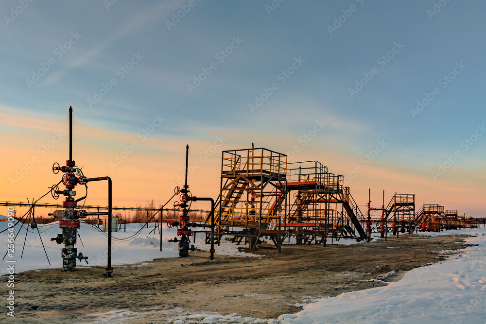 Oil production wells are located in a row at an oil field in western Siberia. Sunset spring sunny day. Oil production wells are located in a row at an oil field in western Siberia. Sunset spring sunny day.