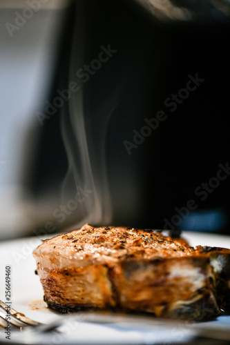 Meat roasted steak  sprinkled with spices on a wooden board with appliances. evaporate from cooked steak