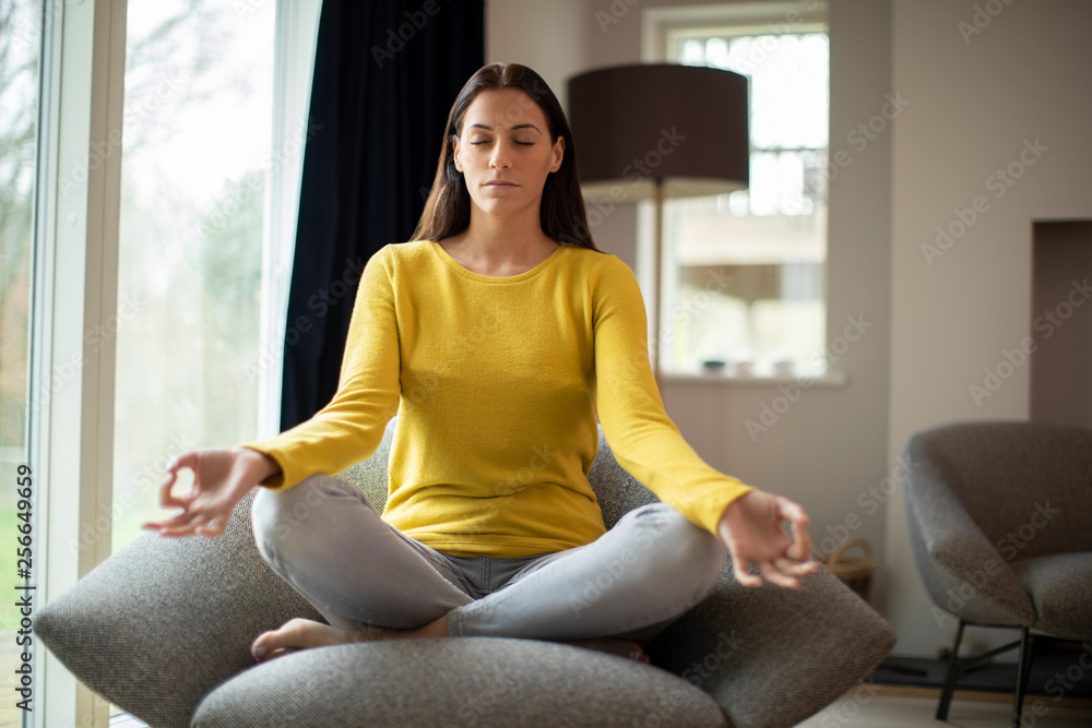 Peaceful Woman Meditating Sitting In Chair At Home