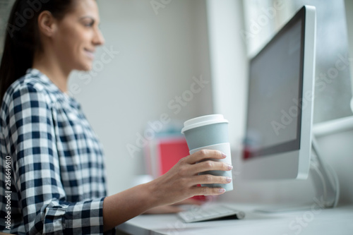 Woman Working At Computer Drinkinking From Reusable Takeaway Cup