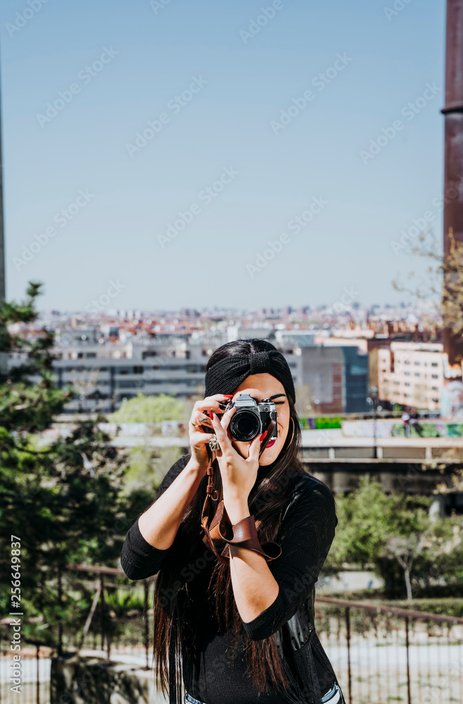 Smiling young woman using a camera to take photo.
