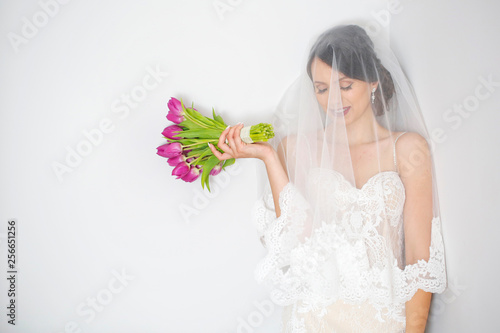 Beauty portrait of a beautiful blonde bride in veil with a bouquet of flowers in his hands