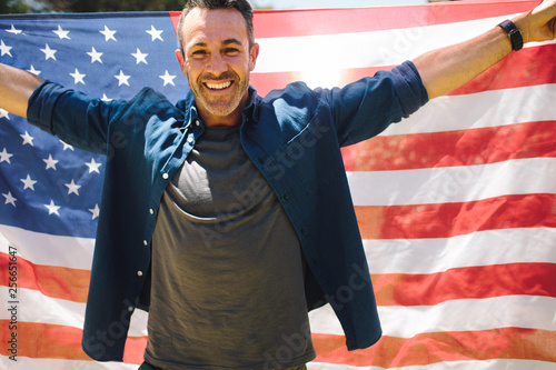 Happy man standing outdoors holding american flag