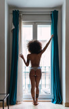 Young naked black woman in panties near window