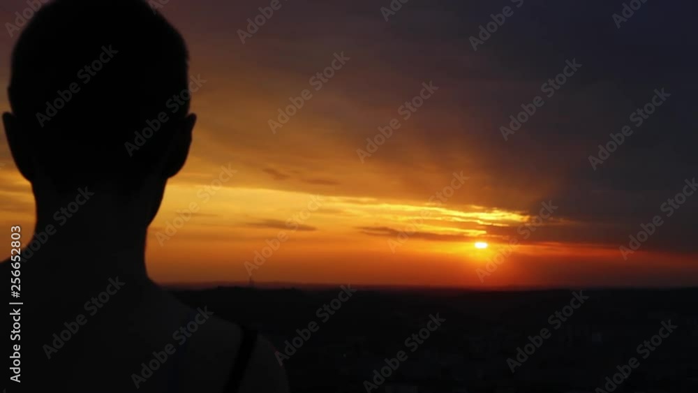 Close-up back view of the beautiful young woman standing over the city looking at wonderful sunset. Close-up back view of the beautiful young woman standing over the city looking at wonderful sunset.