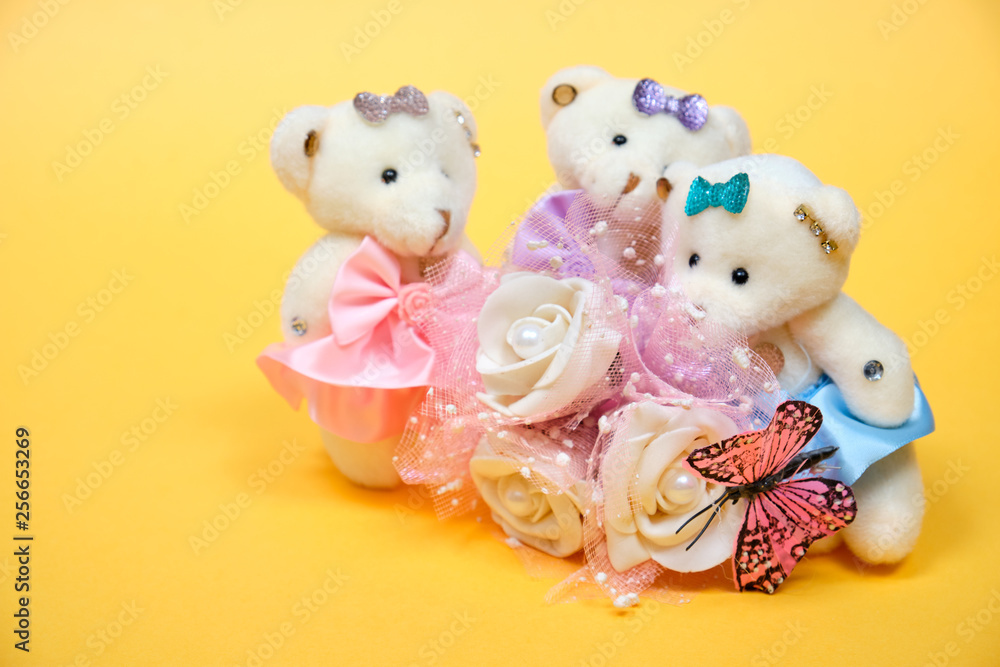 Obraz premium Teddy bears with roses and butterfly on yellow background. Toys