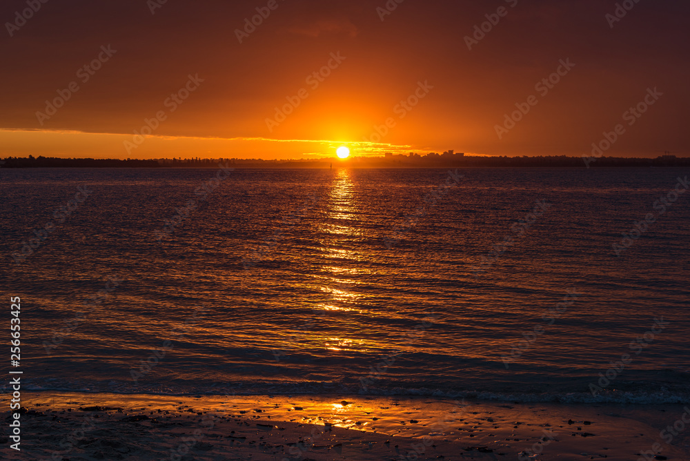 Bright orange red sunset sky over water