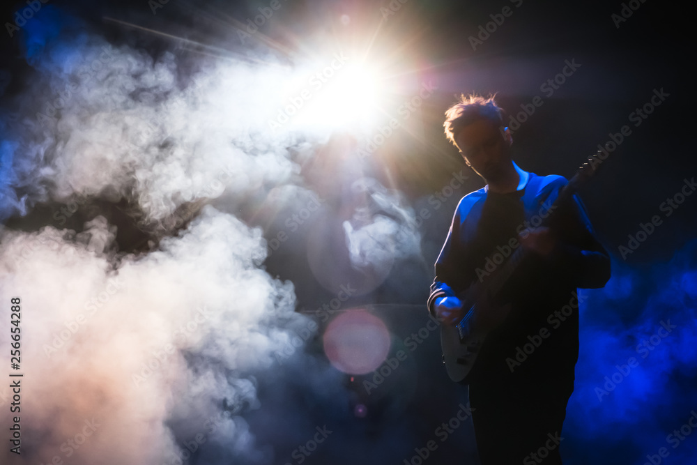 Guitarist playing guitar in dark with blue back light