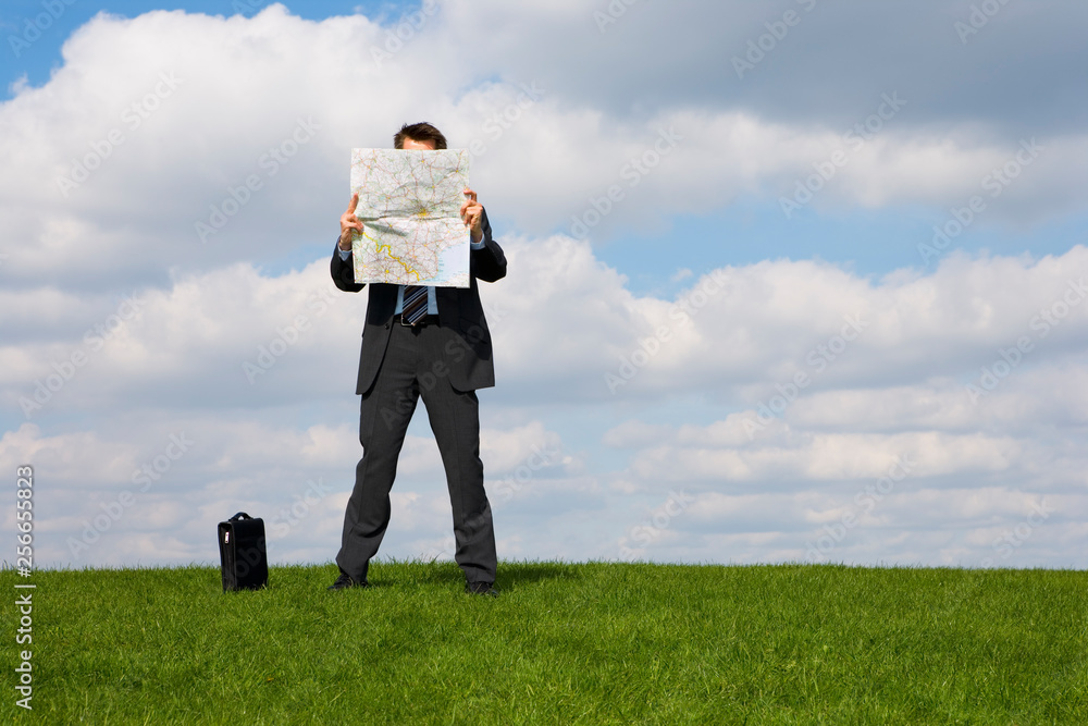 Caucasian businessman reading a map in a field Caucasian businessman reading a map in a field