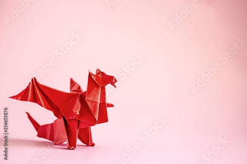 Origami dragon in red on a plain background.  Paper Origami. Сopy space