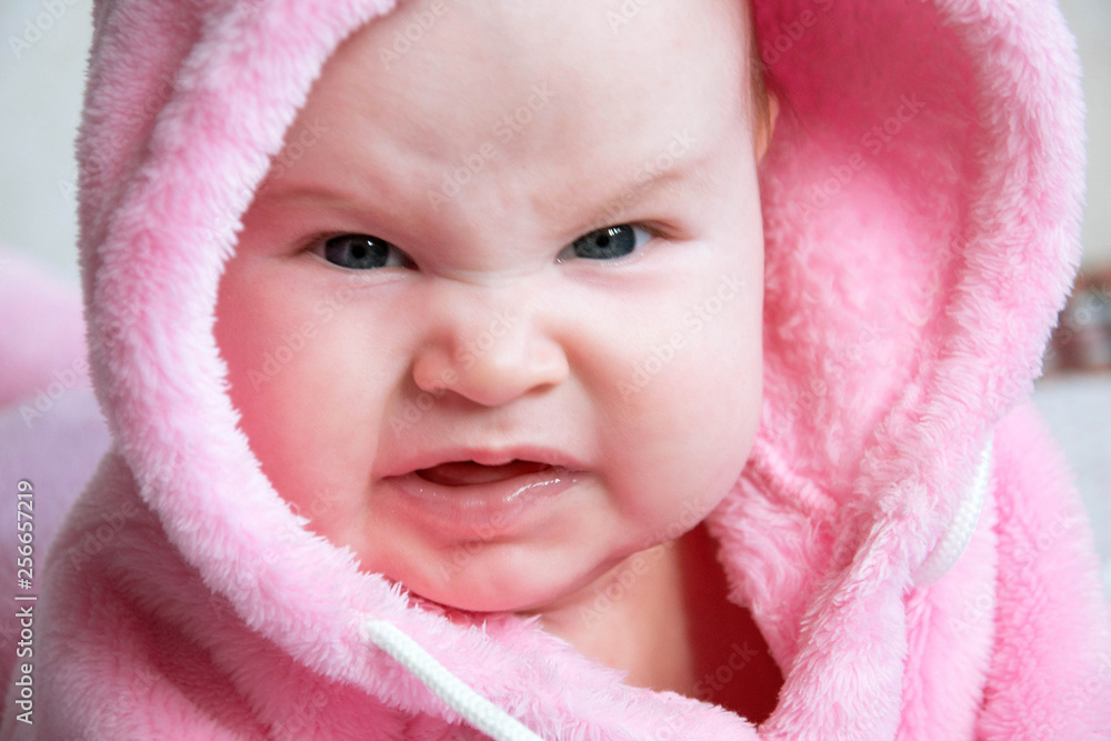 Portrait of a little very bad girl baby. She is dressed in a pink fluffy  blouse with a hood. She has an aggressive facial expression. Funny girl.  Stock Photo | Adobe Stock