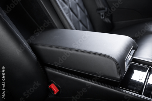Obraz na plátne Close up of armrest between passenger seats of black leather car interior