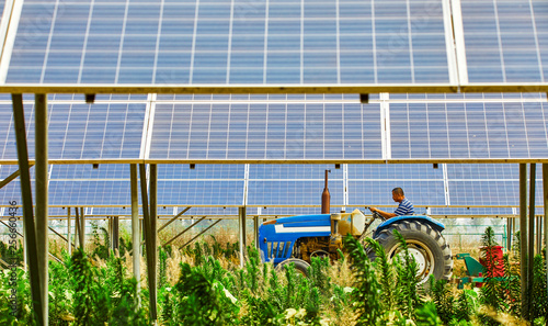 Foto Asian farmer driving a tractor under a solar photovoltaic panel