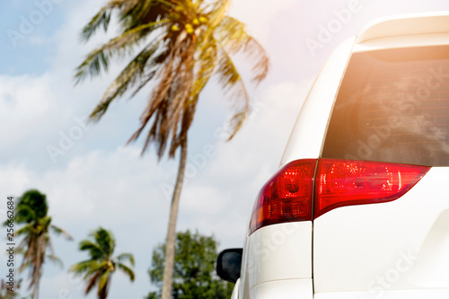 Fototapeta Naklejka Na Ścianę i Meble -  Back side of family car white color stop with nature of coconut tree for trip to travel on the beach with orange light.