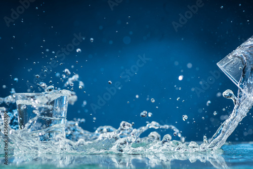 falling small glasses and spilling water on a blue background