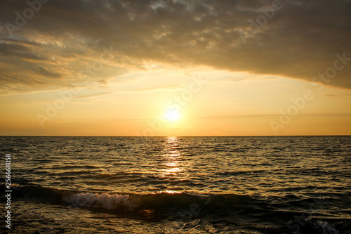 Golden  Fiery sunset on the Black Sea  on the beach. Coast  stones  waves  sun  beautiful sky  clouds. August  Batumi  Georgia. Water  ease  game.