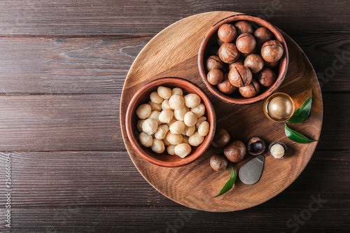 Bowls with macadamia nuts and oil on wooden table photo