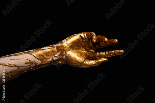 Female hand with golden paint against dark background