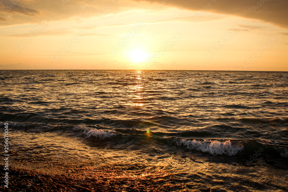 Obraz premium Golden, Fiery sunset on the Black Sea, on the beach. Coast, stones, waves, sun, beautiful sky, clouds. August, Batumi, Georgia. Water, ease, game.