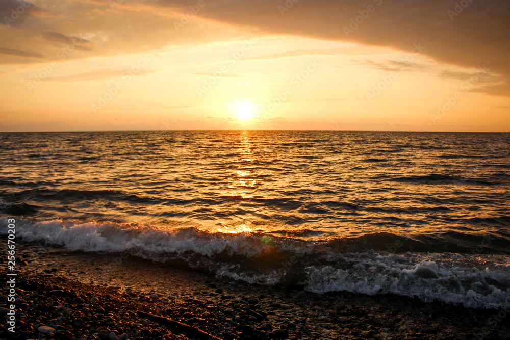 Obraz premium Golden, Fiery sunset on the Black Sea, on the beach. Coast, stones, waves, sun, beautiful sky, clouds. August, Batumi, Georgia. Water, ease, game.