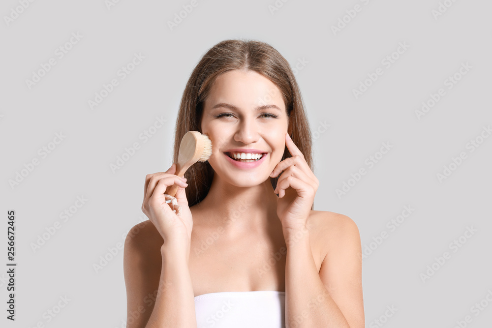 Beautiful young woman with massage brush on light background Beautiful young woman with massage brush on light background