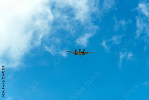 Fototapeta Naklejka Na Ścianę i Meble -  Twin propeller aircraft flying in a blue sky with clouds
