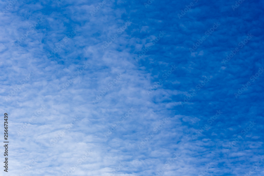Horizontal photo of winter blue clear sky background with white layered clouds without sun