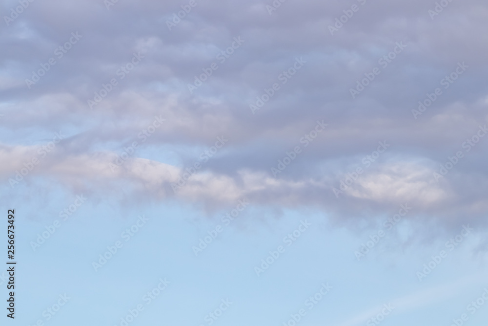 Obraz premium Spring evening sky background with white and grey cumulus clouds on warm sunset