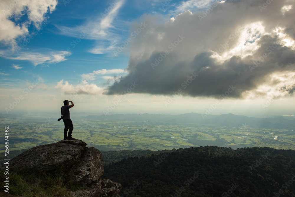 Obraz premium Man standing on top mountain and looking sunset.