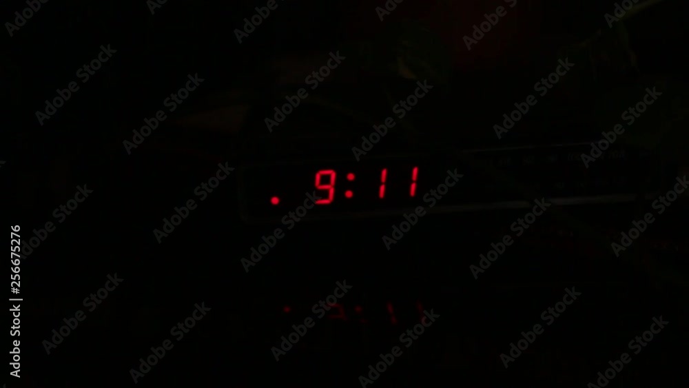 A digital clock flashing 9:11 in the darkness