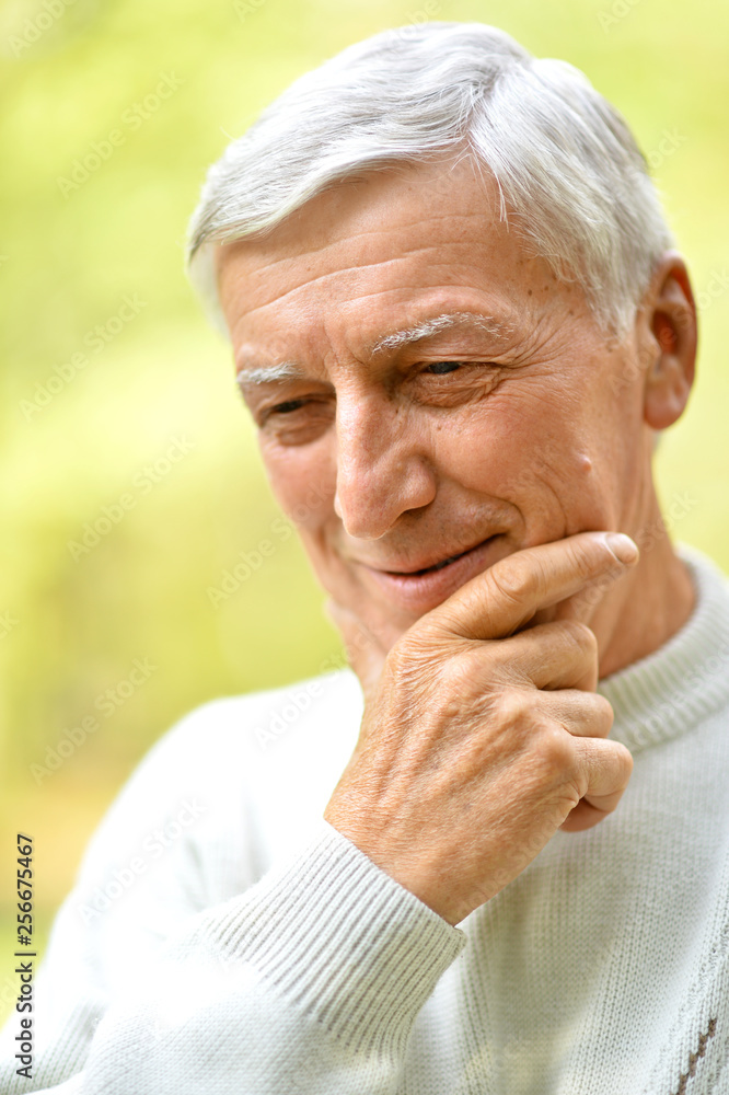 Close-up portrait of senior man in park on green background Close-up portrait of senior man in park on green background