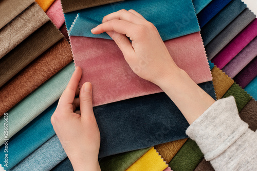 Young woman with fabric samples for curtains at table. Multiple color fabric texture samples selection fabrics for interior decoration. Furniture upholstery