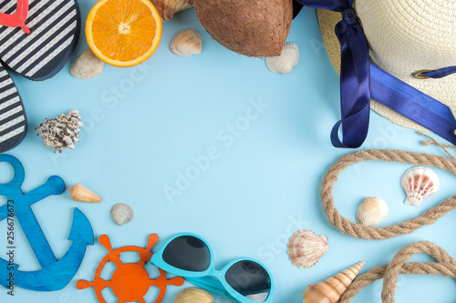 summer accessories with coconut, orange, sun glasses and shells, on a bright blue background. free space. top view. frame