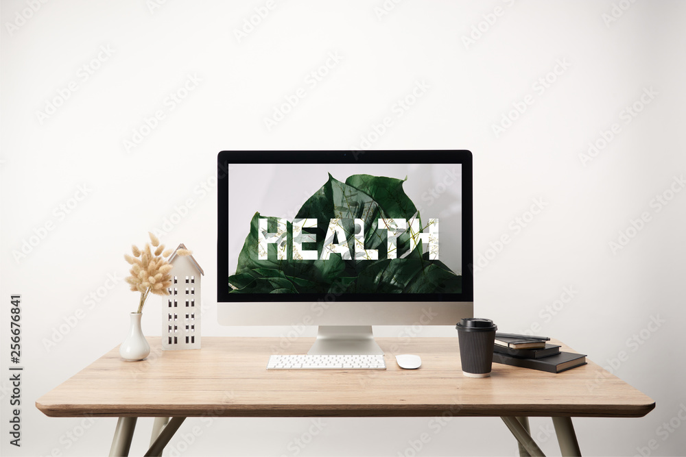 computer with green leaves and health lettering on monitor on wooden desk computer with green leaves and health lettering on monitor on wooden desk