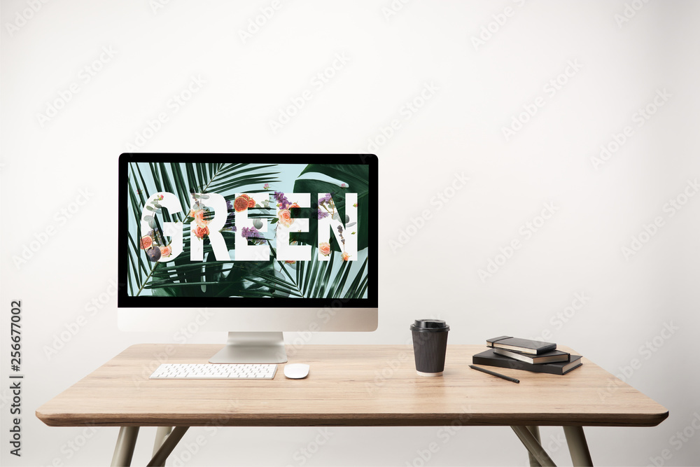 computer with green leaves and green lettering on monitor on wooden desk computer with green leaves and green lettering on monitor on wooden desk