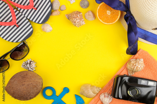 summer accessories with sun glasses, a hat, shells, flip flops, a camera on a bright yellow background. top view. space for text