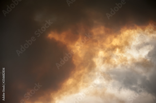 Abstract gray and orange dramatic sky with smoke-filled clouds created from a wildfire.