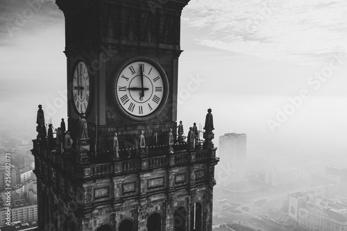 Big old clock face Palace of Culture and Science in foggy Warsaw city Poland