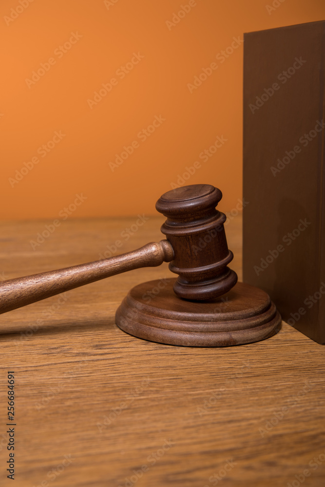 close up of brown book in leather cover and gavel on wooden table isolated on orange close up of brown book in leather cover and gavel on wooden table isolated on orange